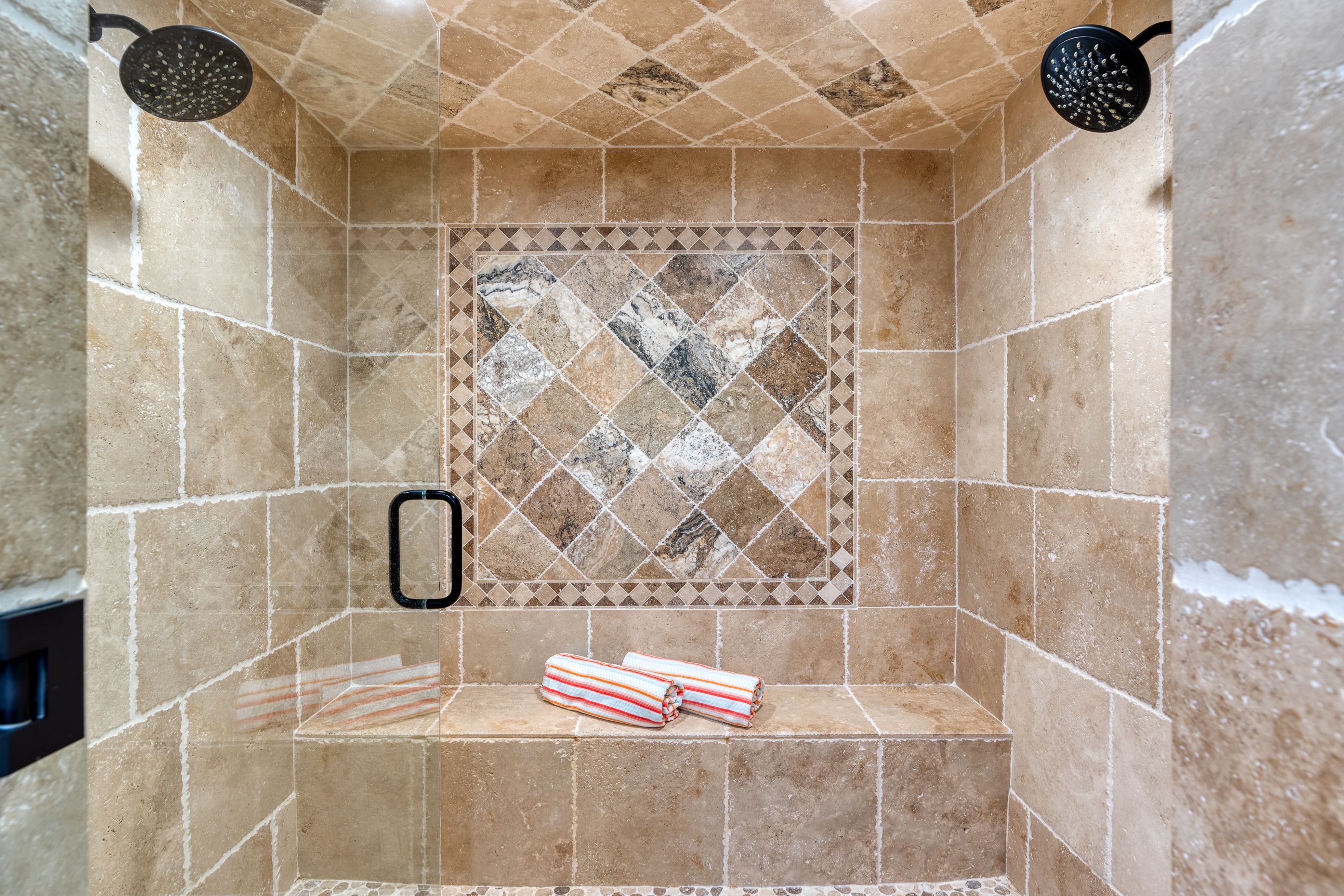 Walk-in tiled shower with rainfall fixture and built-in bench