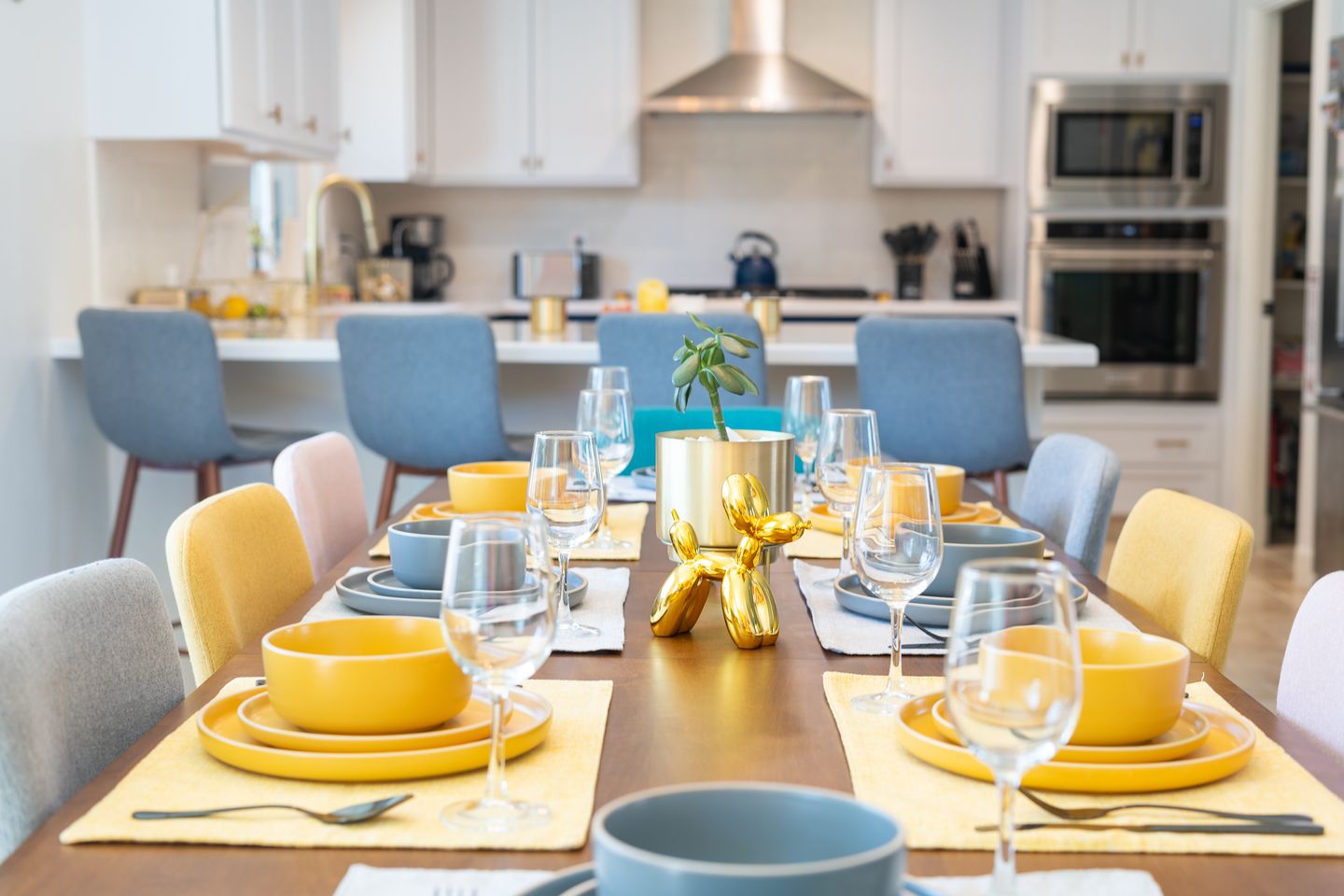 Dining table fully set with yellow dinnerware, glassware, and silverware