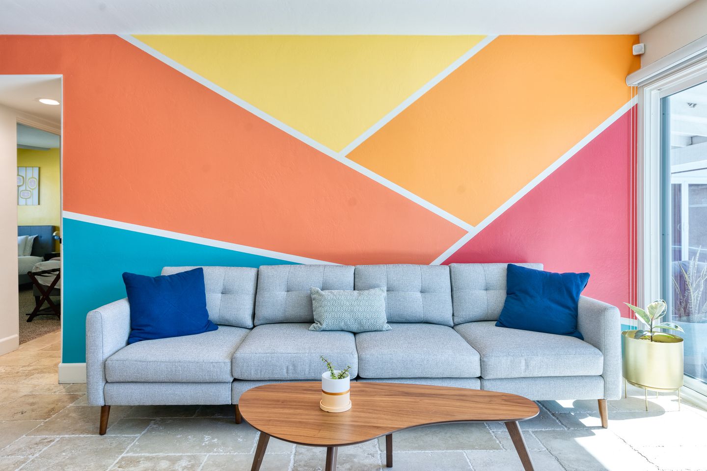 Living room sofa against a geometric tangerine, pink, and yellow feature wall