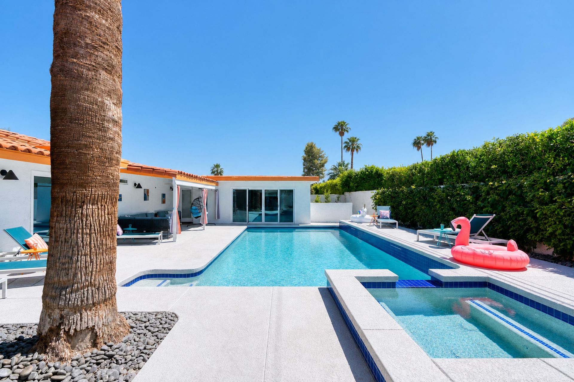 Wide view of the private pool and raised spa with a flamingo float beneath palms