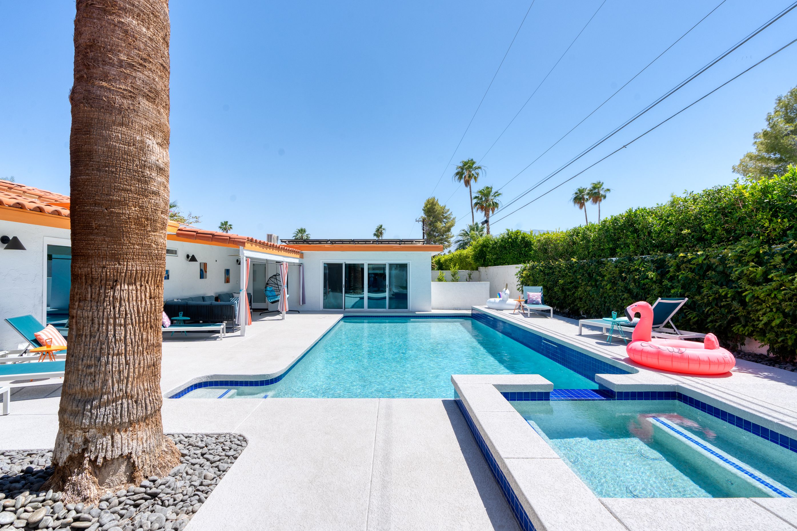 Wide view of the private pool and raised spa with a flamingo float beneath palms