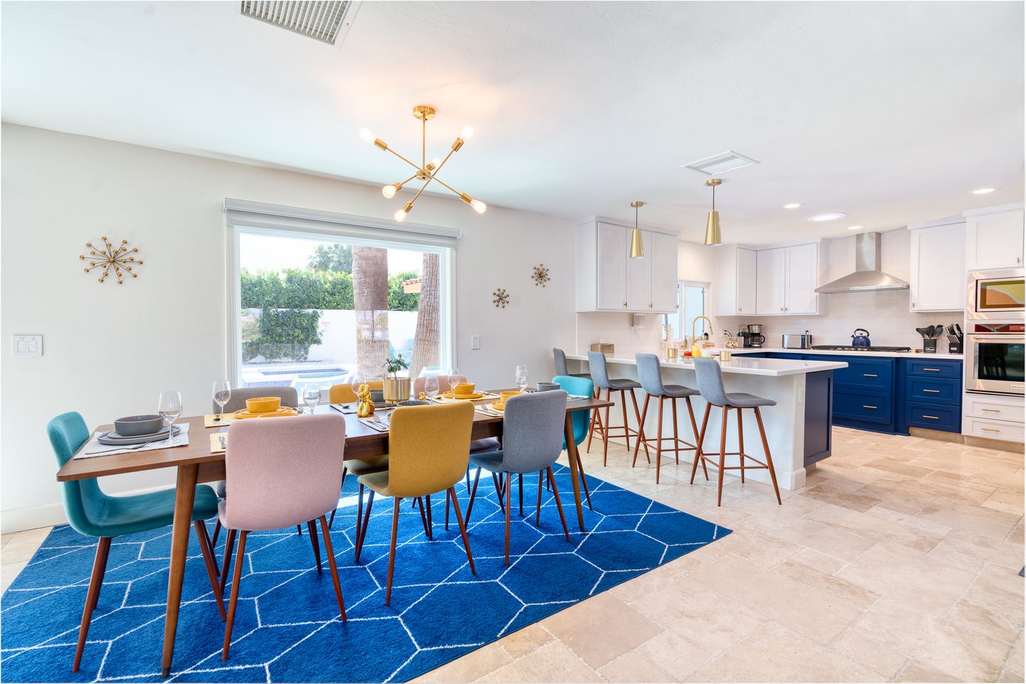 Open kitchen and dining room with cobalt cabinetry and a geometric rug
