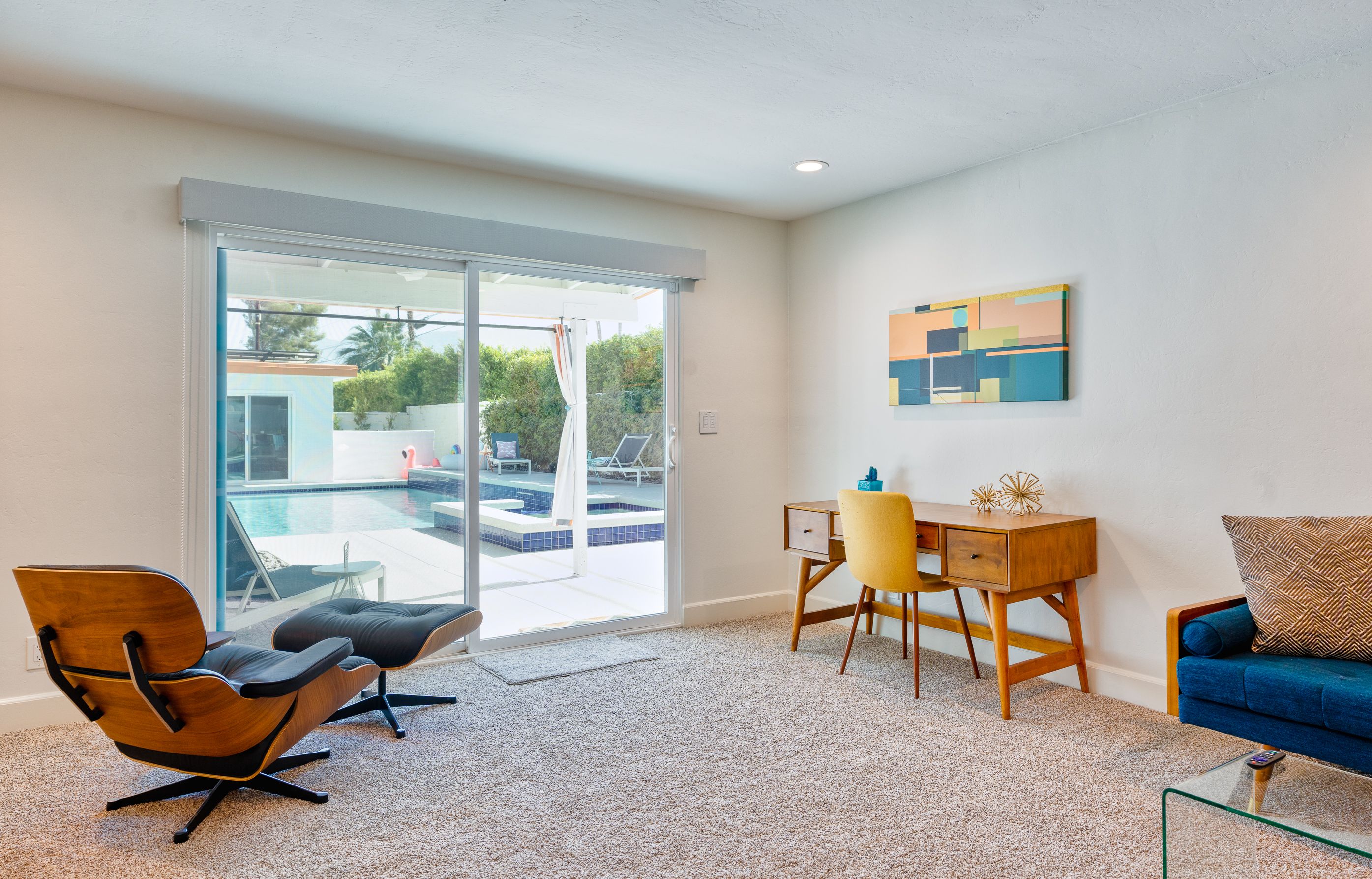 Sunny lounge with mid-century chairs and a view toward the pool courtyard