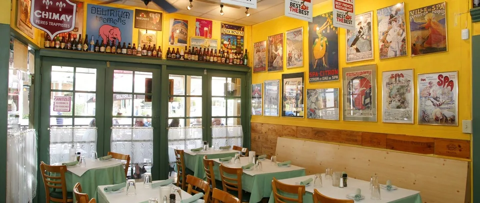 Pomme Frite’s yellow dining room is lined with vintage French posters and small set tables.