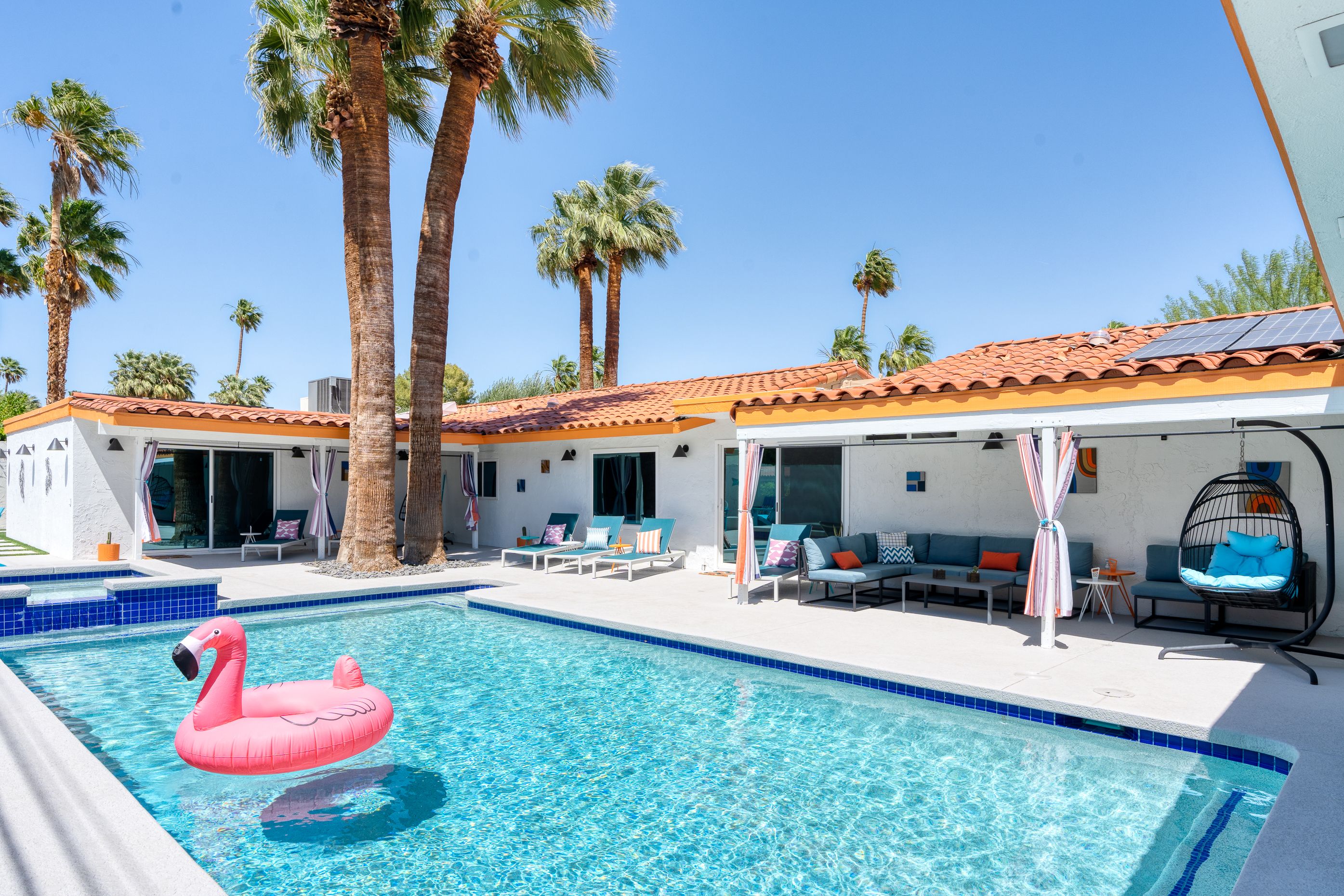 The Orchid House pool with colorful floaties beneath tall palms on a sunny day