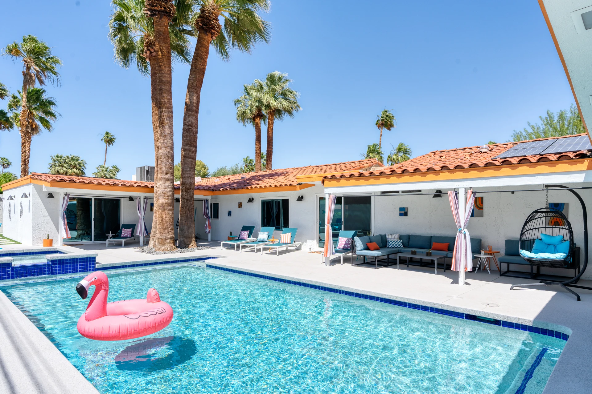Turquoise pool with a pink float, framed by tall Palm Springs palms