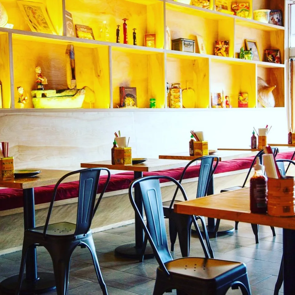 A bright yellow display wall and red banquette frame the dining room at Rooster and the Pig.